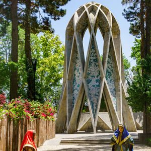 The view of Hakim Omar Khayyam Tomb Architecture in a garden with lots of pink flowers in the clay vases, Iransense Travel Agency